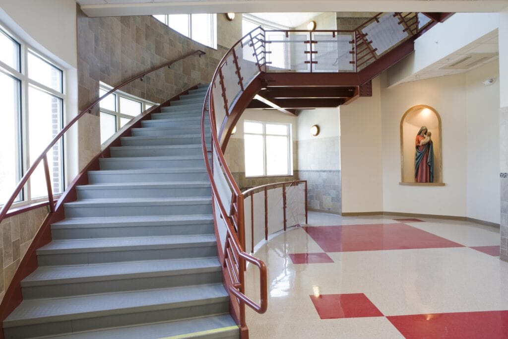 Handrail staircase inside a religious school with modern flooring and interior design.