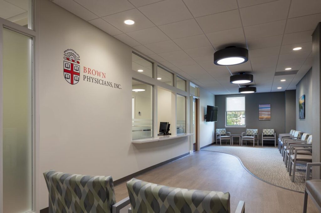 Modern medical office waiting room with comfortable chairs, reception window, and calming artwork, showcasing professional healthcare interior design by Deslandes Construction Inc.