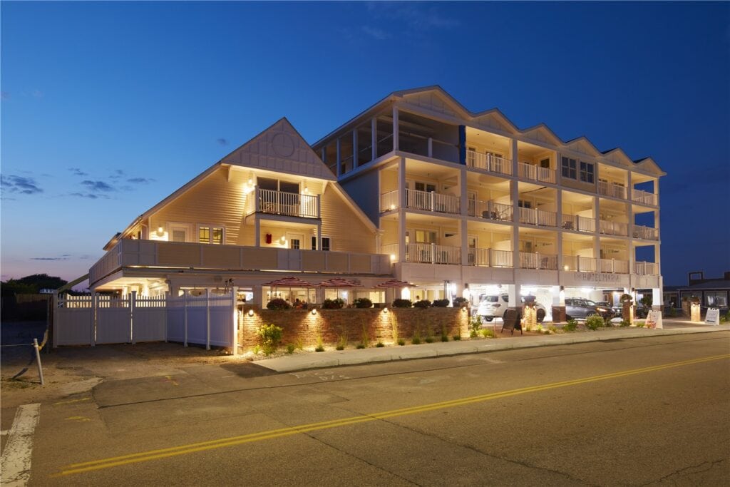 Modern multi-story hotel building with illuminated balconies and parking lot, showcasing professional construction and architectural design by Deslandes Construction Inc.