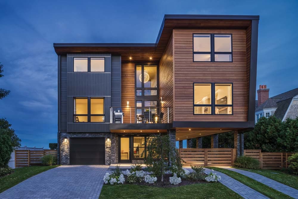 Pawtuxet Contemporary home exterior with modern wood siding, large windows, and evening lighting