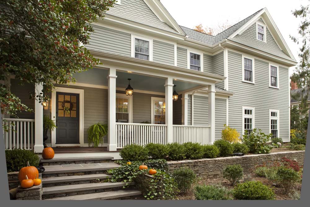 Barrington Federal Colonial exterior after renovation designed around a historic brick fireplace, featuring a farmer’s porch and updated facade
