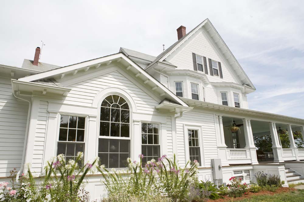 Warwick Neck Victorian showing a renovated Victorian-style home with white siding, a wraparound porch, and a prominent arched window