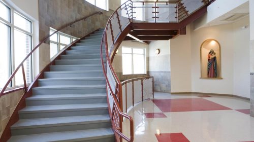 Handrail staircase inside a religious school with modern flooring and interior design.