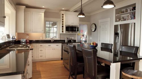 Barrington Cape interior reframing kitchen with island seating, pendant lights, and stainless steel appliances