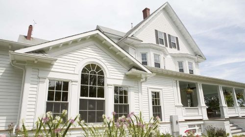 Warwick Neck Victorian showing a renovated Victorian-style home with white siding, a wraparound porch, and a prominent arched window